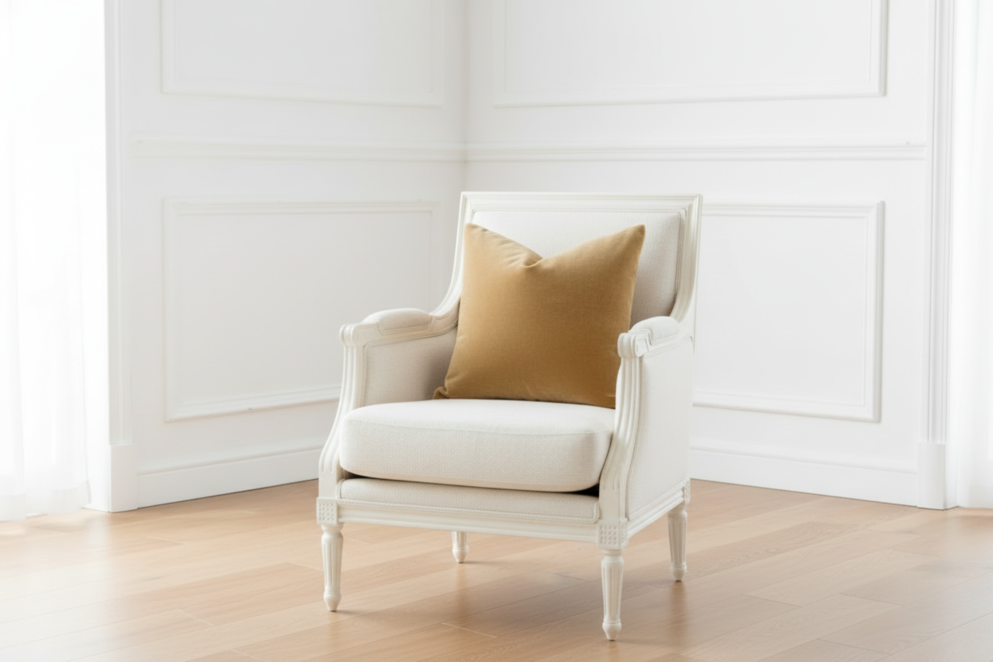 White armchair with a mustard yellow pillow against a white wall.